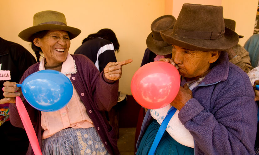 Two older women blow up balloons for a celebration in Peru 